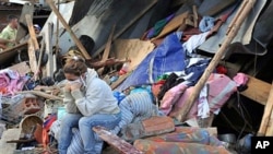 A woman sits in front of her home, destroyed by a landslide that buried dozens of houses and left dozens trapped beneath mud and rubble following weeks of drenching rains, in Bello, northwestern Colombia, 06 Dec. 2010