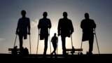 Four Palestinian friends, who were injured during conflicts, walk by the sea at Gaza&#39;s small fishing harbor.