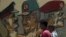 People walk in front of a wall sprayed with stencilled paintings depicting the Egyptian military council members in Tahrir Square in Cairo May 24, 2012.