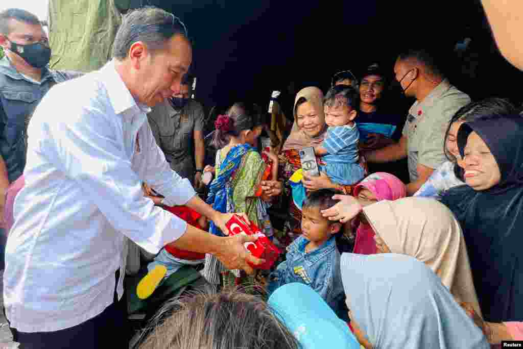 Presiden Joko Widodo membagikan makanan kepada anak-anak di tempat penampungan sementara selama kunjungannya ke lokasi yang terkena dampak gempa di Cianjur, provinsi Jawa Barat, Selasa 22 November 2022. (Laily Rachev/Istana Kepresidenan RI via Reuters)&nbsp;