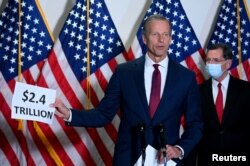 Senator John Thune (R-SD) holds a sign, which refers to the spending for the coronavirus relief bill, while speaking at a news conference at the U.S. Capitol in Washington, Oct. 20, 2020.