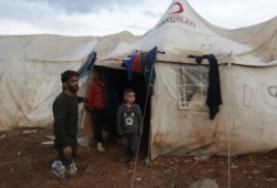 Ahmad Hamra, stands with his children outside a tent at an internally displaced Syrian camp, in northern Aleppo near the Syrian-Turkish border, Syria, Feb. 17, 2021.