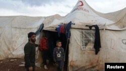 Ahmad Hamra, stands with his children outside a tent at an internally displaced Syrian camp, in northern Aleppo near the Syrian-Turkish border, Syria, Feb. 17, 2021. 
