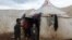 Ahmad Hamra, stands with his children outside a tent at an internally displaced Syrian camp, in northern Aleppo near the Syrian-Turkish border, Syria, Feb. 17, 2021. 