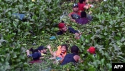 FILE - Migrants cross through the banks of the Rio Grande River to the United States, as seen from Matamoros, state of Tamaulupas, Mexico, on May 9, 2023. The Biden administration is planning to restrict the number of people allowed to request asylum, sources say.
