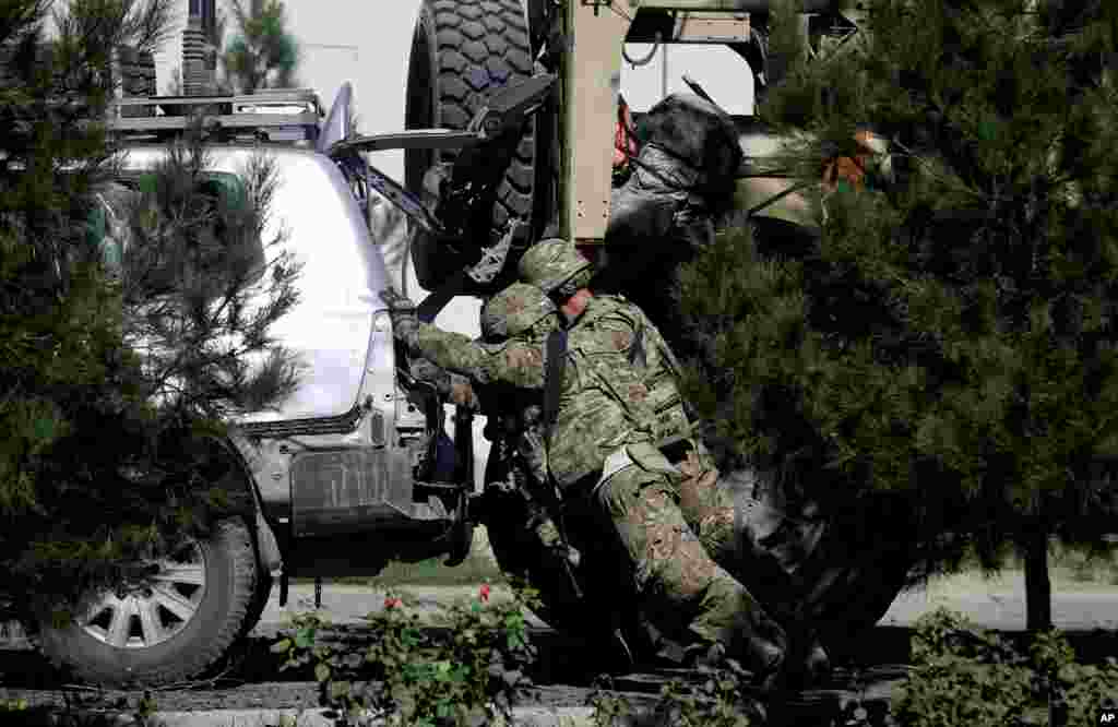 U.S. military forces push a damaged vehicle at the site of a suicide attack near a U.S. military camp in Kabul, Afghanistan, Sept. 16, 2014.