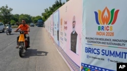 Кур'єр їде на електросамокаті повз встановлений при дорозі банер саміту БРІКС із зображенням прем'єр-міністра Індії Нарендри Моді. Нью-Делі, 10 вересня 2026 року. Фото: AP/Manish Swarup
