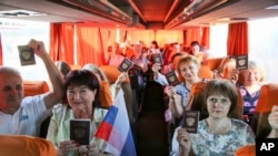 People travelling to Russia show their Russian passports at a bus stop in Donetsk, eastern Ukraine, June 27, 2020.