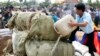 A Cambodian officer, right, pours fuel into some three tones of various drugs are seized in the nation wide of this country at the outskirt of Phnom Penh, Cambodia, file photo. 