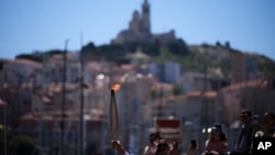 La antorcha olímpica es alzada durante el relevo en Marsella, sur de Francia, el jueves 9 de mayo de 2024.