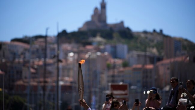 La antorcha olímpica es alzada durante el relevo en Marsella, sur de Francia, el jueves 9 de mayo de 2024.