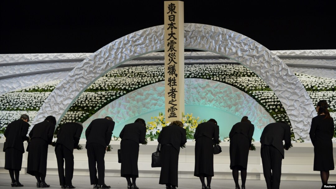 Keluarga korban bencana gempa bumi dan tsunami memberi hormat ke hadapan altar bertabur bunga chrysanthemums dalam peringatan tiga tahun bencana nasional tersebut di Tokyo (11/3).