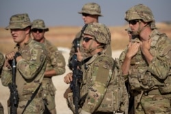 FILE - U.S. soldiers wait to board vehicles at an undisclosed location in Syria, Nov. 11, 2019. A coalition commander said at the time that the partnership with Syrian Kurdish forces remained focused on fighting the Islamic State group.