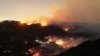 Flames and smoke from the Palisades Fire surround a home (C) in the community of Topanga, California, on January 9, 2025.