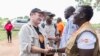 FILE - U.S. Democratic Sen. Chris Coons, left, tours Bidi Bidi in Uganda, one of the largest refugee settlements in the world, Aug. 13, 2019.