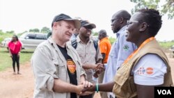 FILE - U.S. Democratic Sen. Chris Coons, left, tours Bidi Bidi in Uganda, one of the largest refugee settlements in the world, Aug. 13, 2019.