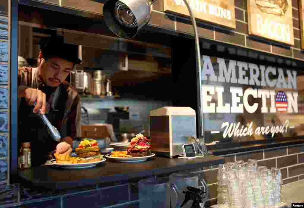 Juru masak J.S. Burgers Café, Yasuhito Fukui, mempersiapkan Mr. dan Mrs. Burger yang mewakili kandidat kepresidenan AS Hillary Clinton dan Donald Trump, di warung hamburger di Tokyo, Jepang.&nbsp; Bahan-bahan burger yang mewakili Clinton mencerminkan tradisi khas Chicago, sementara burger Trump mencerminkan tradisi khas New York.