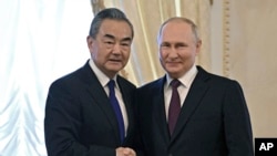 Presiden Rusia Vladimir Putin, kanan, dan Menteri Luar Negeri China Wang Yi berjabat tangan sebelum pertemuan di Istana Konstantinus di St. Petersburg, Rusia, Rabu, 20 September 2023. (Foto: via AP)