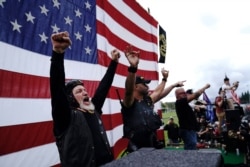 FILE - Members of the Proud Boys cheer on stage as they and other right-wing demonstrators rally in Portland, Oregon, Sept. 26, 2020.