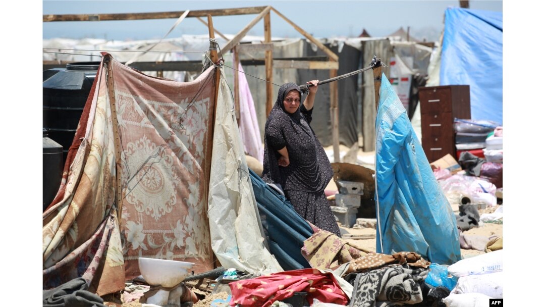 Seorang perempuan pengungsi Palestina berdiri di samping barang bawaannya ketika orang-orang menyelamatkan diri dari wilayah Mawassi di barat daya Khan Younis di selatan Jalur Gaza, 28 Juni 2024. (Foto: Bashar Taleb/AFP)