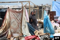 ایک فلسطینی خاتون نے خان یونس میں چادریں لٹکا کر رہنے کی عارضی جگہ بنا لی ہے۔ 28 جون 2024