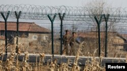 FILE - North Korean soldiers patrol behind a border fence near the North Korean town of Sinuiju, March 31, 2017. 