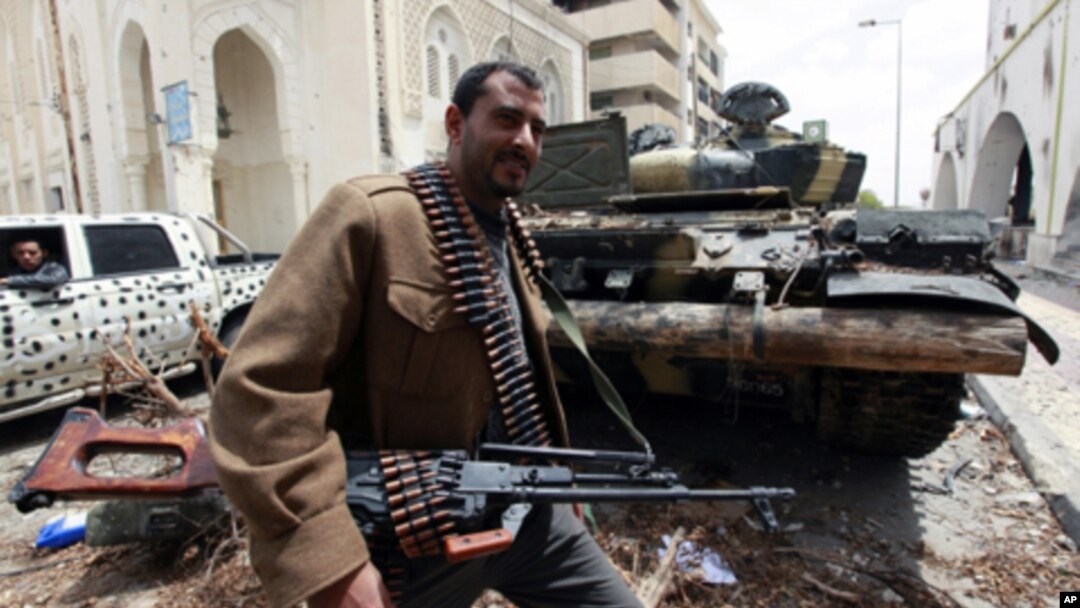 A rebel fighter walks beside a captured Gaddafi forces tank in Tripoli street April 22, 2011. Rebel fighters pushed Gaddafi forces off the upper part of Tripoli Street in central Misrata during an overnight offense.