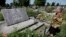 FILE - A woman stands near a mass grave and a monument in the village of Chlaniow, Poland, that holds the bodies of Poles killed in a 1944 attack on the village by the Nazi SS-led Ukrainian Self Defense Legion, June 19, 2013.