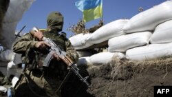 Ukrainian soldier peers over sandbags in a trench close to the small eastern city of Pervomaysk, near Lugansk, Sept. 13, 2014.