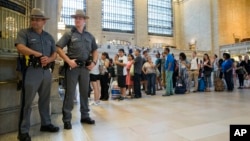 New York state police officers stand guard as travelers line up to buy train tickets at Grand Central Terminal in New York, July 1, 2016.