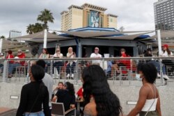 People sit at an outdoor terrace outside the Tampa Convention Center a day before Super Bowl LV, as the spread of the coronavirus disease continues, in Tampa, Fla., Feb. 6, 2021.