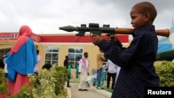 FILE - A Somali boy plays with a toy model of a rocket-propelled grenade (RPG) in Mogadishu, July 6, 2016. Children have been maimed and killed playing with real weapons, ordnance and explosive devices.