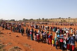 People stand in a queue to receive food aid amid the coronavirus pandemic, at the Itireleng informal settlement, near the Laudium suburb in Pretoria, South Africa, May 20, 2020.