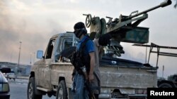 Fighters of the Islamic State of Iraq and the Levant (ISIL) stand guard at a checkpoint in the northern Iraq city of Mosul, June 11, 2014.