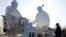 FILE - A man walks past a roadside sculpture which promotes China's one-child policy, in Beijing.