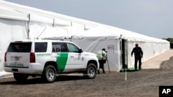 Un guardia de seguridad ingresa a una nueva instalación temporal de la Oficina de Aduanas y Protección Fronteriza en Donna, Texas, el jueves 2 de mayo de 2019. (AP Foto/Eric Gay)