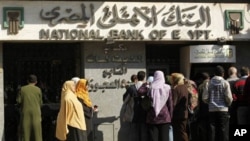 People in Cairo wait to withdraw money from the bank. Egypt's currency has dropped in value to its lowest level in 6 years, February 3, 2011