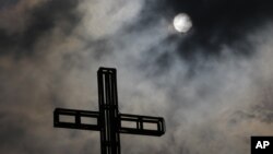 Dark clouds partially cover the sun in the sky above a church on Easter Sunday in suburban Quezon city, north of Manila, Philippines, April 5, 2015. 