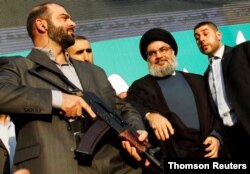 FILE - Lebanon's Hezbollah leader Sayyed Hassan Nasrallah (2nd R), escorted by his bodyguards, greets his supporters at an anti-U.S. protest in Beirut's southern suburbs.