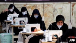 Iranian women, members of the paramilitary organization Basij, make face masks and other protective items at a mosque in Tehran amid the novel coronavirus pandemic, April 5, 2020.