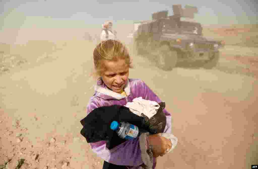 A displaced Iraqi girl reacts as she flees her home in Mamoun district as Iraqi forces battle with Islamic State militants, in western Mosul, Iraq.