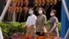 在中国北京街头戴着口罩的妇女经过一个摆放风车玩具的摊位（2022年9月13日）。
