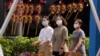 戴著口罩的行人走過北京街頭一個售賣傳統風車玩具的商舖。 （2022年9月13日）