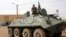 Fighters of the Islamic group, the Movement for Oneness and Jihad in West Africa [MUJAO] - an Al-Qaida offshoot - stand guard on a tank abandoned by the Malian Army, near Gao airport, Mali, August 7, 2012.