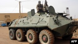 Fighters of the Islamic group, the Movement for Unity and Jihad in West Africa [MUJAO] - an Al-Qaida offshoot - stand guard on a tank abandoned by the Malian Army, near Gao airport, Mali, August 7, 2012.