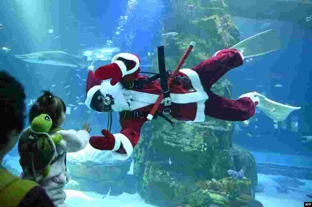 A diver dressed as Santa Claus waves to visitors during a Christmas-themed underwater show at Lotte World Aquarium in Seoul. (Photo by Jung Yeon-je / AFP)