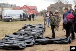 Ukrainian Prosecutor General Iryna Venediktova, center, looks at the exhumed bodies of civilians killed during the Russian occupation in Bucha, on the outskirts of Kyiv, Ukraine, Friday, April 8, 2022. (AP Photo/Efrem Lukatsky, File)