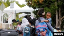 Yon gwoup moun ki idantifye tèt yo kòm ayisyen ki soti Etazini e kap mande azil sou fwontyè Kanada. 7 out 2017. (Foto: REUTERS/Christinne Muschi) 