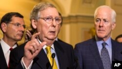 FILE - Senate Majority Leader Mitch McConnell accompanied by fellow senators meets with reporters on Capitol Hill.