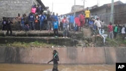 FILE—People stand along a river as they watch houses in riparian land being demolished in the Mukuru area of Nairobi, Kenya, May. 7, 2024.